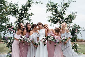 Beautiful elegant slim smiling bridesmaids in delicate pink beige summer dress on the wedding ceremony.