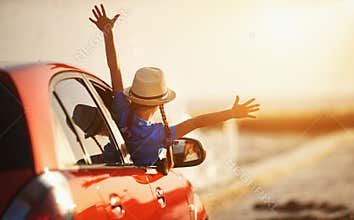 Happy child girl goes to summer travel trip in car