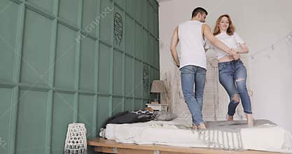 Young romantic couple are dancing, smiling and flirting standing in bed. Relationship and love concept.