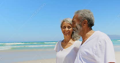Side view of happy active senior African American couple walking on beach in the sunshine 4k