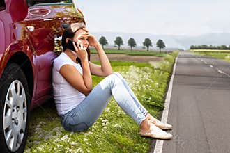 Woman Sitting On Road Near Breakdown Car