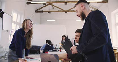 Camera follows happy middle aged bearded businessman checking young multiethnic employees work at light modern office.