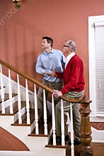 Man helping senior father climb stairs at home