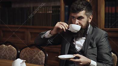 Luxury lifestyle, success, elegance, tea time concept. Aristocrat sits in luxury interior and drinks tea or coffee