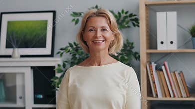 Portrait of happy mature lady looking at camera and smiling standing in office