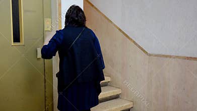 Black haired woman avoiding lift due to claustrophobia