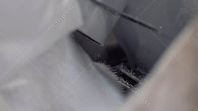 Small white balls poured into machine from large bag closeup