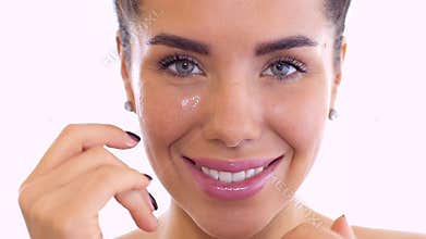 Beautiful woman rubs cream in face at white background
