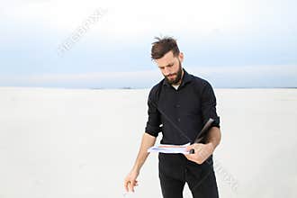 Geographer male smoking carrying out research on seaside.