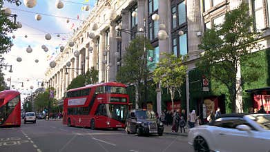 Taxis and red double decker London buses driving past Selfridges, Oxford street, London, England