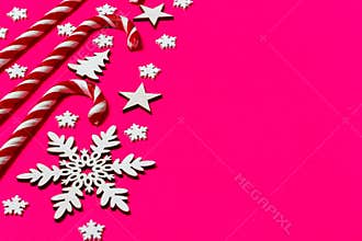 Christmas candy cane lied evenly in row on pink background with decorative snowflake and star. Flat lay and top view