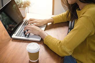Digital lifestyle working outside office. Woman hands typing laptop computer with blank screen on table in coffee shop.