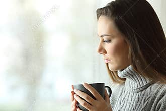 Sad woman looking down in a rainy day