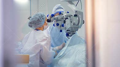 A surgeon and as assistant are engrossed during an eye treatment.