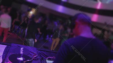 Guy playing music, many people clubbing, moving on dancefloor
