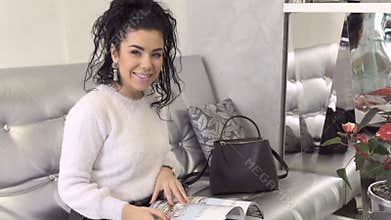 Beautiful smiling brunette with magazine sit at sofa