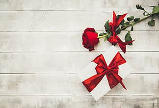 Red roses and gift box on a wooden table. Happy Valentines Day