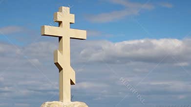 Orthodox stone cross against blue sky background, belief in God, religion