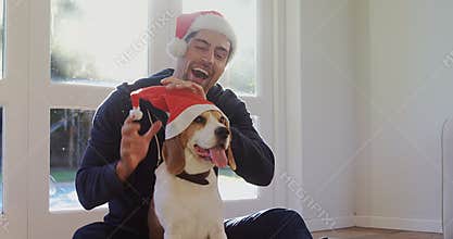 Smiling young man putting santa cap on his pet dog 4K 4k