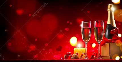 Valentine`s Day romantic dinner. Champagne, candles and gift box over red background