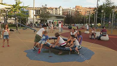 Kids of different age playing on playground roundabout, happy children smiling