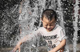 Little boy in the street fountain water column
