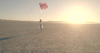 A girl with balloons walking in the desert Lake El Mirage. Aerial Drone. October 2017