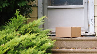 Delivery parcel on the porch of the house. The man is laying the box near the door. Delivery to the door