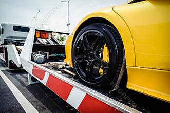 Flat bed tow truck loading a broken vehicle