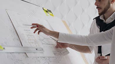 Close-up of two architects discussing a project to build a new project depicted drawings of which are depicted on a