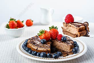 Big chocolate cheesecake with blueberry strawberry raspberry on a round plate.
