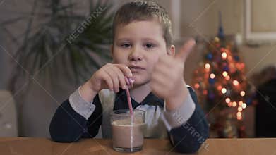 Kid drinking a tasty drink through a straw at home