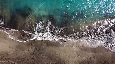 Top view of a woman in red dress walking barefoot along wet sand ocean beach