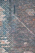 Brick wall with many layers of old paint and different patterns