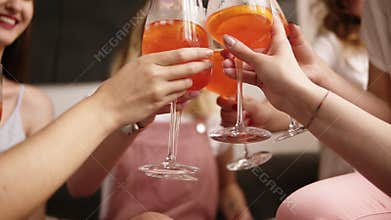 Hen party. Aim footage of a clinking with cocktails in girls hands. Female friends tell gossip and having fun. Laughing