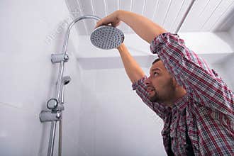 Serviceman repairing shower head in bathroom