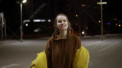 Young expansive woman sensually dancing outside in yellow jacket. Feel free, smiling. Handhelded footage