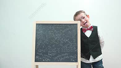 Funny child with eyeglasses and uniform make faces close chalk board, make fun of learning