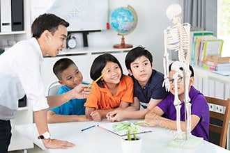 Asian teacher explains a human body structure to little pupil