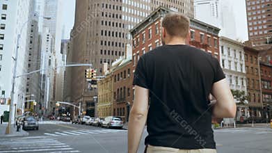Young handsome businessman with documents standing near road, going to work in office in New York, America. Slow motion.