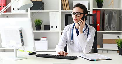 Doctor is talking on phone and looking at monitor