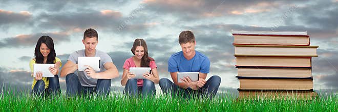Composed image of students studying with tablets next to books