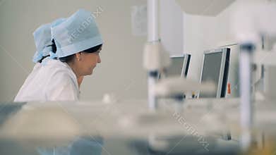 Nurses use computers, while a machine performs tests. 4K.