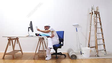 House painter man with a computer and magnifying glass looks at color samples and search the internet, e-commerce and shop paint c
