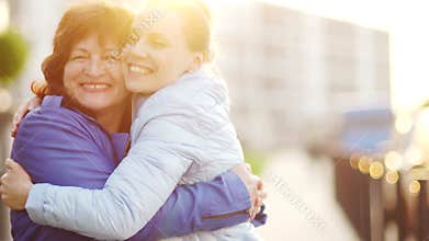 Happy mother and her aduit daughter. Women gently embrace and joyfully look at the camera. Family traditions. Mothers