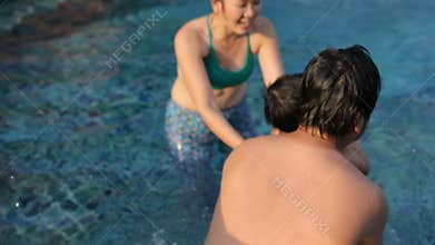Asian family playing with happiness relaxing in water pool