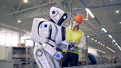 Male factory employee is switching a robot on after which it snads up and starts drilling