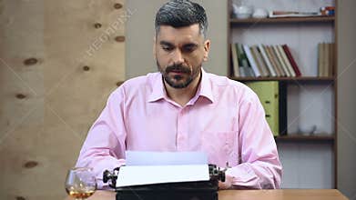 Concentrated old-school author typing book on vintage typewriter in his office