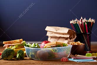 Back to School concept, school supplies, biscuits, packed lunch and lunchbox on white desk, selective focus, close-up.