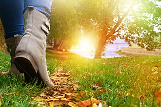 Woman in grey shoes and jeans walking on the autumn forest path